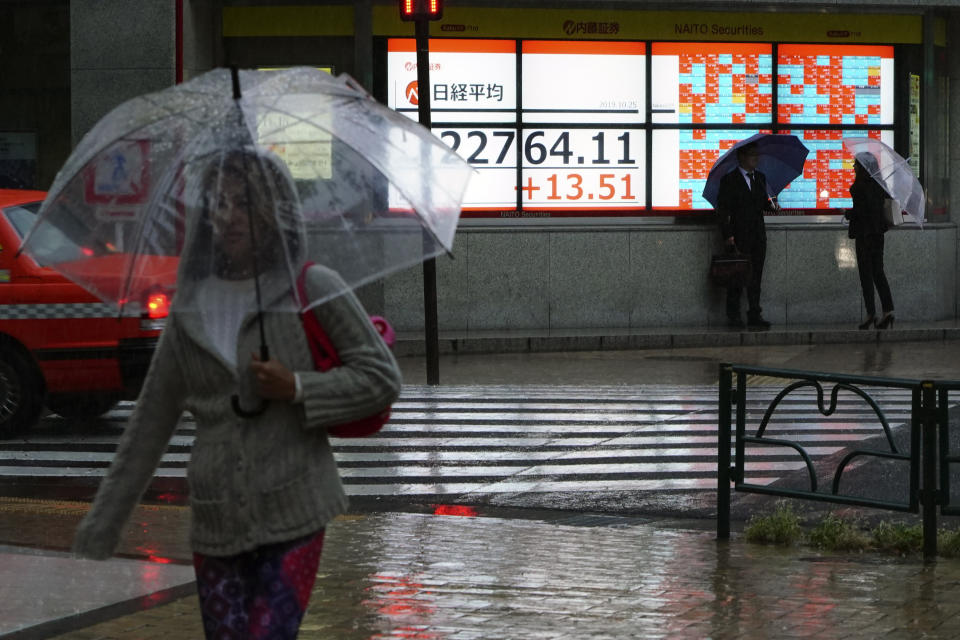 People stand near an electronic stock board showing Japan's Nikkei 225 index at a securities firm in Tokyo Friday, Oct. 25, 2019. Asian shares were mixed Friday, after Wall Street indexes posted modest gains, cheered by solid profits and forecasts from U.S. technology companies. (AP Photo/Eugene Hoshiko)