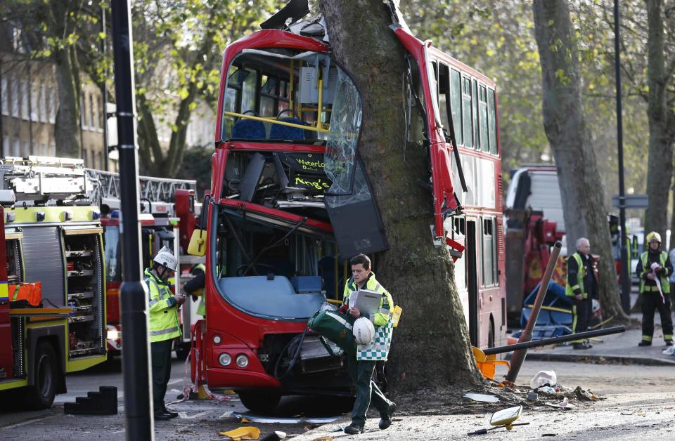 A members of the emergency services walks in front of a bus which crashed into a tree in Kennington, south London