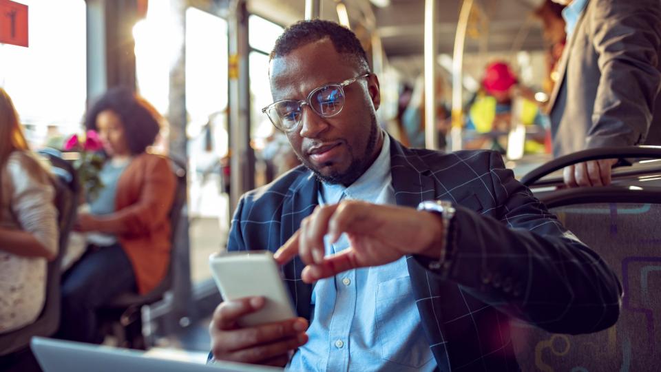 A man sitting in a bus checks his phone.