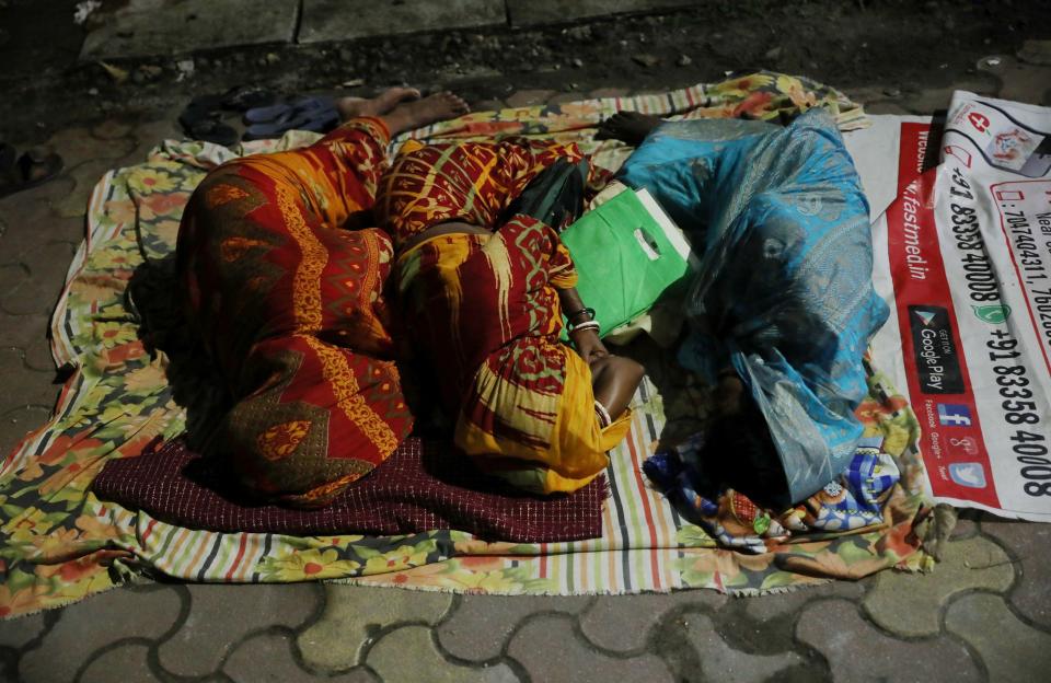 Women sleep while waiting in a queue to collect a token to receive a dose of COVISHIELD vaccine, manufactured by Serum Institute of India, outside a vaccination centre in Siliguri, in the eastern state of West Bengal, India, October 6, 2021. Picture taken on October 6, 2021. REUTERS/Rupak De Chowdhuri