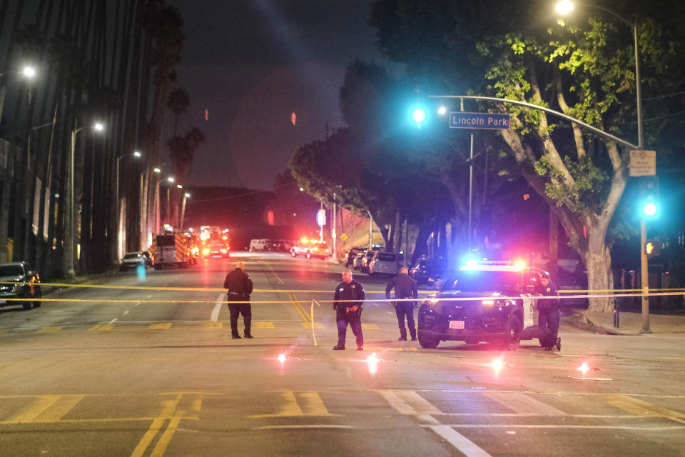 Police officers stand guard near a crime scene where three Los Angeles police officers were shot, Wednesday, March 8, 2023, in Los Angeles. Police said the officers were hospitalized and in stable condition. (AP Photo/Ringo H.W. Chiu)