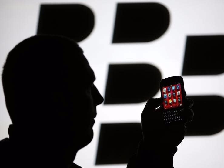 A man is silhouetted against a video screen with the Blackberry logo as he pose with a Blackberry Q10 in this photo illustration taken in the central Bosnian town of Zenica, September 21, 2013.  REUTERS/Dado Ruvic 