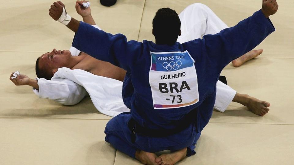 Leandro Guilheiro de Brasil (azul) celebra la victoria sobre Víctor Bivol de Moldavia (blanco) en la competencia por la medalla de bronce de judo masculino -73 kg durante los Juegos Olímpicos de Verano de Atenas 2004.