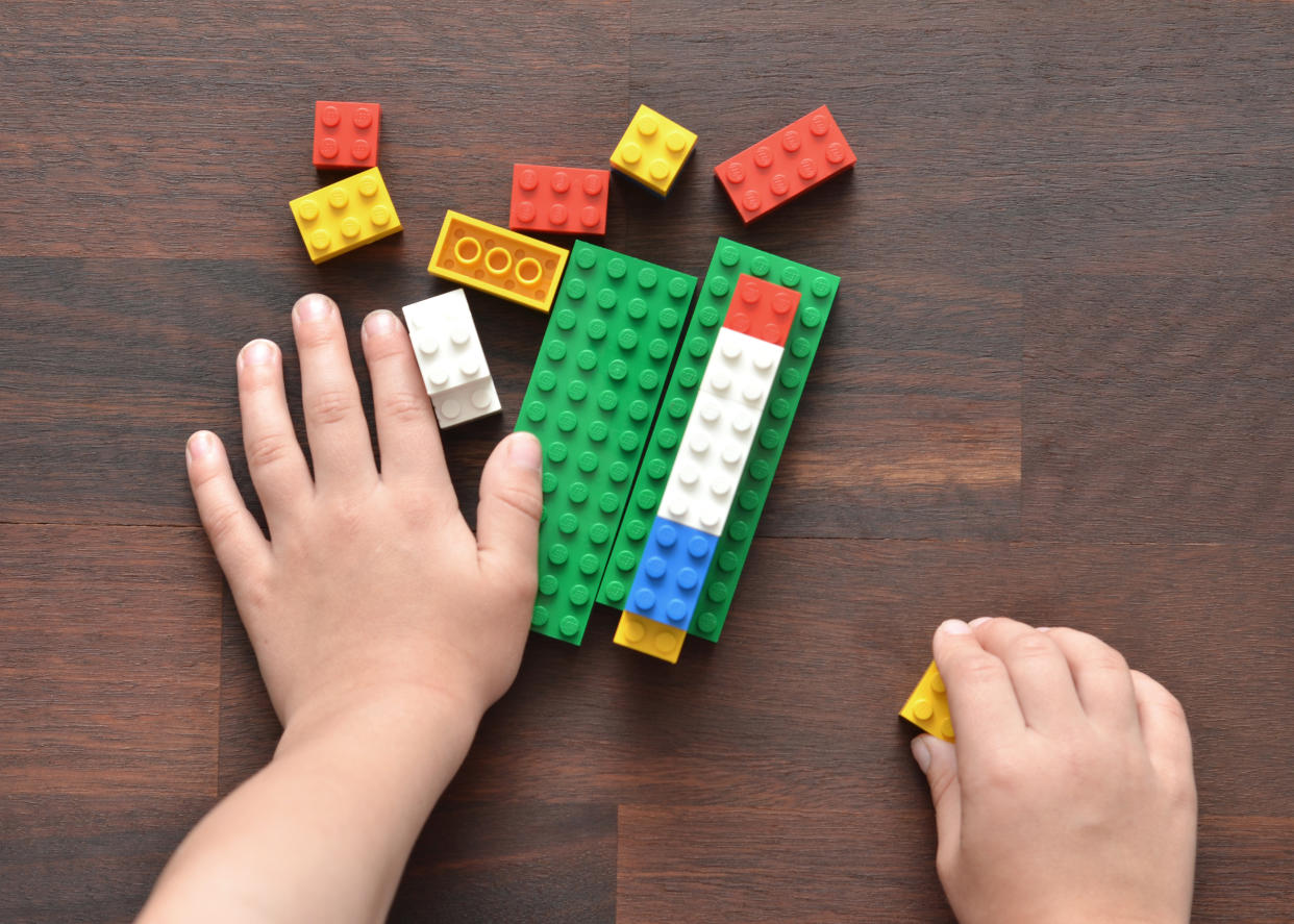 Vancouver, B.C., Canada -- May 28, 2015:Closeup of a 5 year old boy playing with Lego building blocks on a wood table.  Lego is a popular toy brand that is available worldwide.  