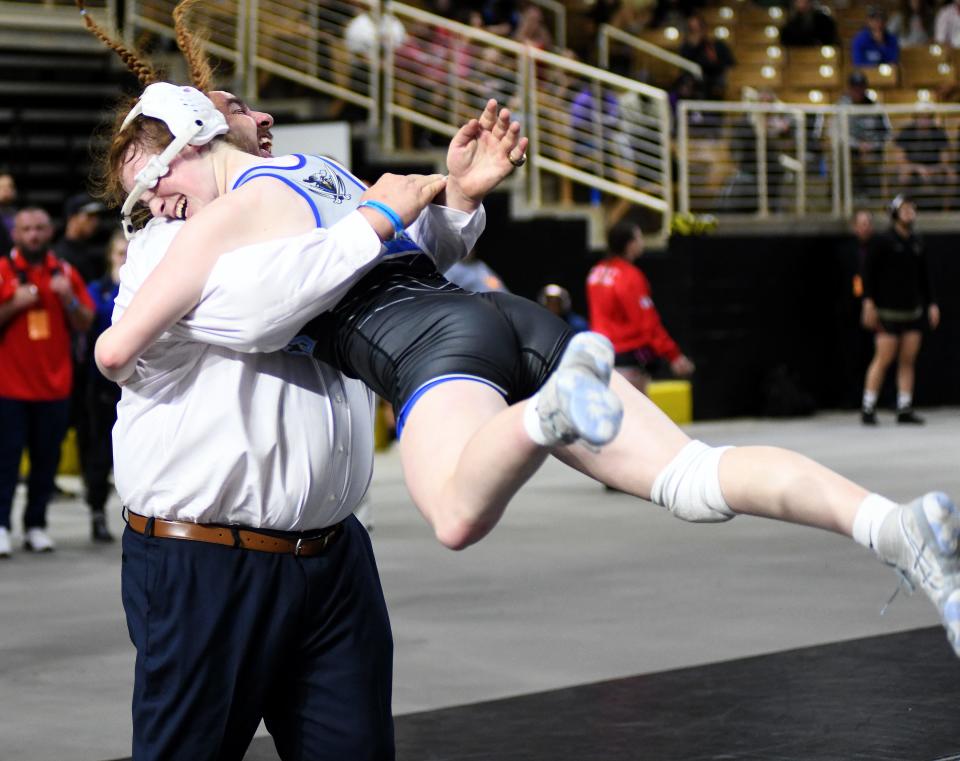 Kendall Bibla flies into the arms of coach Mike Fries after Bibla's 15-4 major decision victory against Bartram Trail's Katherine Stewart in the girls 145-pound final Saturday, March 4, 2023, at the FHSAA State Wrestling Championships at the Silver Spurs Arena in Kissimmee.