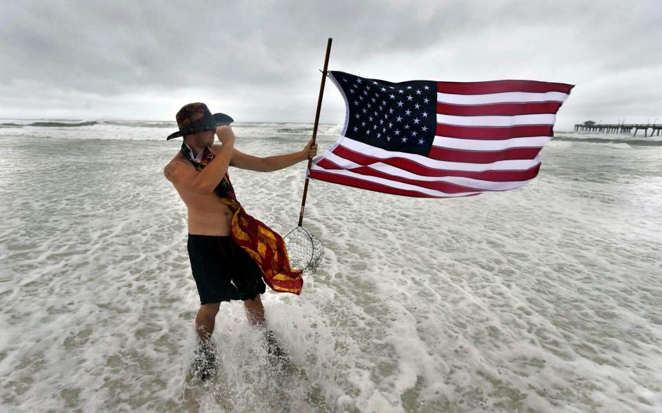 Corbin Boyce holds an American flag on the beach near Fort Walton Beach in Florida - Northwest Florida Daily News/Devon Ravine