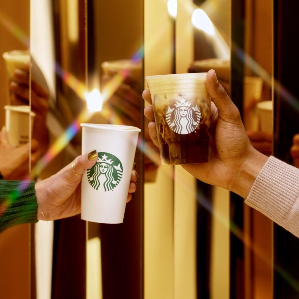 Photo of two cups of coffee held aloft in a toast