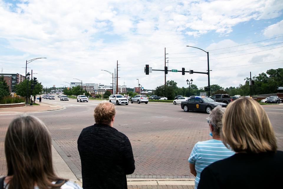 People pay their respects from the corner of Fifth Street and First Avenue during a funeral procession for Coralville police Sgt. John Williams on Monday. Williams, 59, died after suffering a medical emergency while on duty July 3.