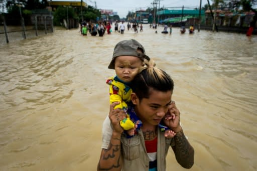 A man carries a baby through floodwaters in the Bago region, some 68 km from Yangon