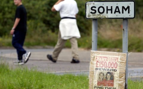 Two boys walk by a reward poster for ten-year-old schoolgirls Holly Wells and Jessica Chapman that was tied to the village sign of Soham in Cambridgeshire on August 19, 2002. - Credit: DAN CHUNG/Reuters