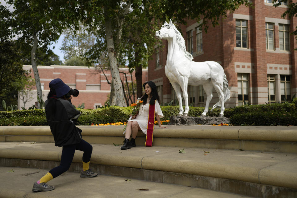 A recent graduate has their photograph taken in front of the school's mascot on the USC campus Thursday, April 25, 2024, in Los Angeles. The University of Southern California has canceled its main graduation ceremony and dozens of students were arrested on other campuses as protests against the Israel-Hamas war continued to spread. (AP Photo/Jae C. Hong)