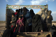 Women and children exit the back of a truck, part of a convoy evacuating hundreds out of the last territory held by Islamic State militants in Baghouz, eastern Syria, Friday, Feb. 22, 2019. (AP Photo/Felipe Dana)