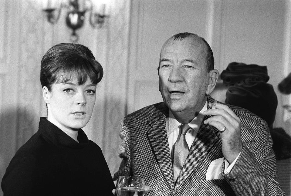 Rosalind Russell and Noël Coward standing together, with Coward holding a cigarette and a drink, dressed in formal attire