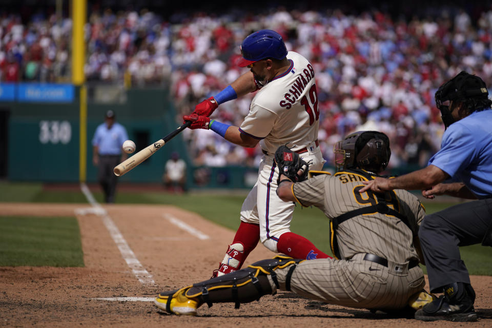 Philadelphia Phillies' Kyle Schwarber, left, hits a run-scoring single against San Diego Padres pitcher Tim Hill during the eighth inning of the first baseball game in a doubleheader, Saturday, July 15, 2023, in Philadelphia. (AP Photo/Matt Slocum)