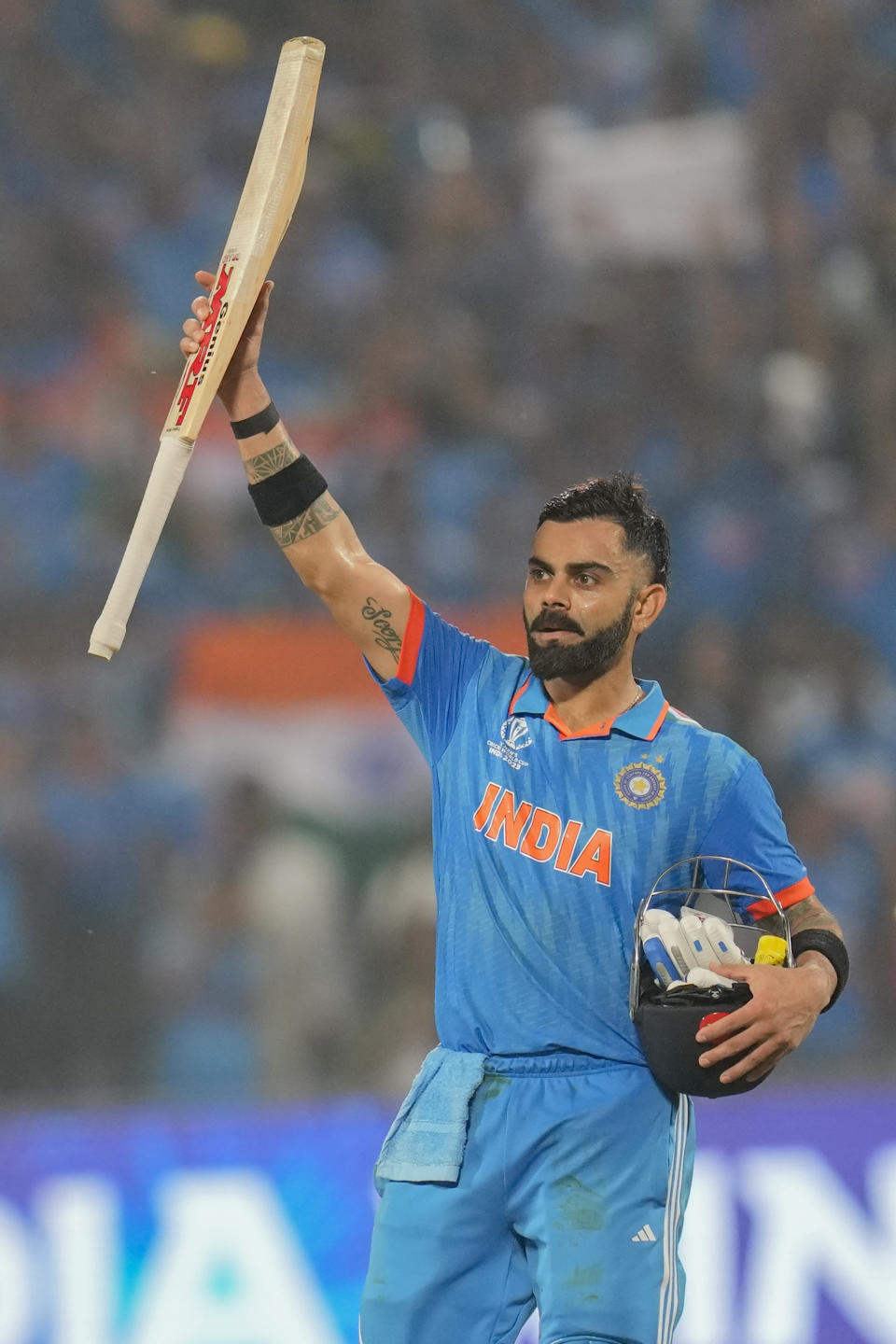 India's Virat Kohli raises his bat as he celebrates his century during the ICC Men's Cricket World Cup match between Bangladesh and India in Pune, India, Thursday, Oct. 19, 2023. (AP Photo/ Rafiq Maqbool)