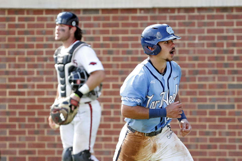 North Carolina's Tomas Frick (52) celebrates his run on a wide pitch as Arkansas's Michael Turner (12) stands nearby during the seventh inning of an NCAA college super regional baseball game in Chapel Hill, N.C., Sunday, June 12, 2022. (AP Photo/Karl B DeBlaker)
