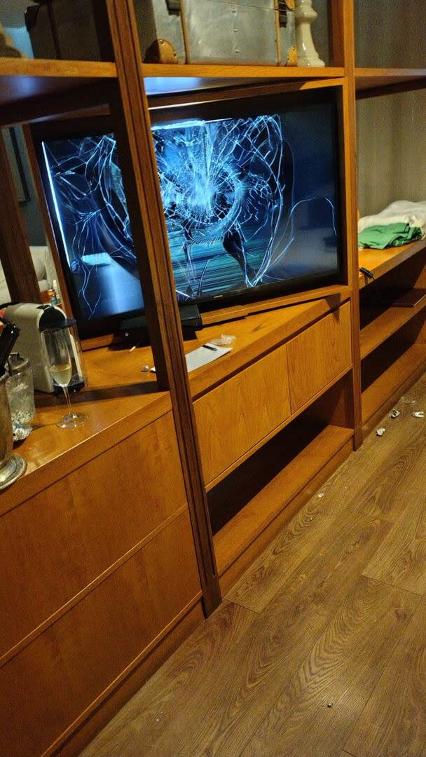 El televisor led de la habitación estaba destruido y se observan botellas de y copas con bebida alcohólica