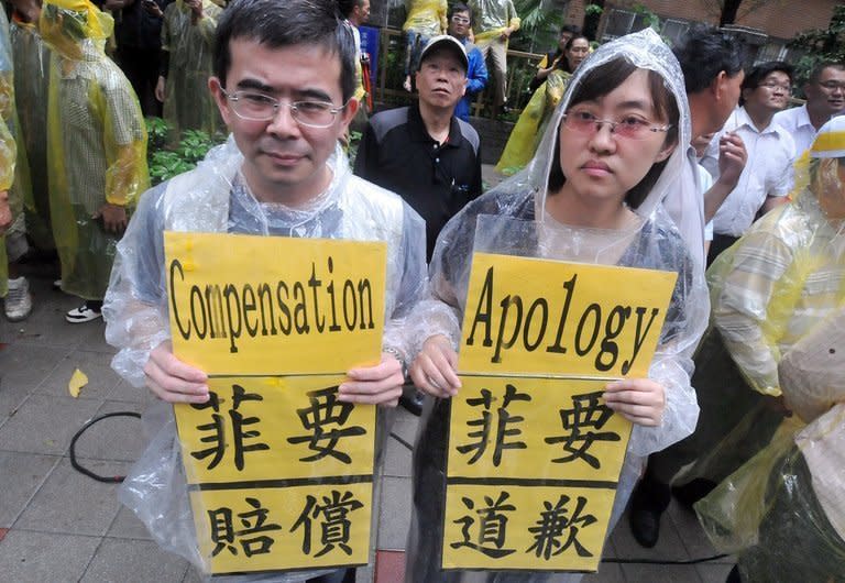 People hold protest signs outside the Philippine de facto embassy in Taipei, on May 13, 2013