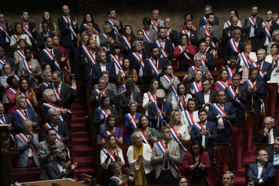 Members of the National Assembly stand and applaud to pay homage to children victims of a knife attack in a town the French Alps, Thursday, June 8, 2023 in Paris. France's interior minister Gerald Darmanin says Thursday June 8, 2023 that an attacker with a knife injured children and others in a town in Annecy, French Alps. In a short tweet, he said police have detained the attacker (AP Photo/Lewis Joly)