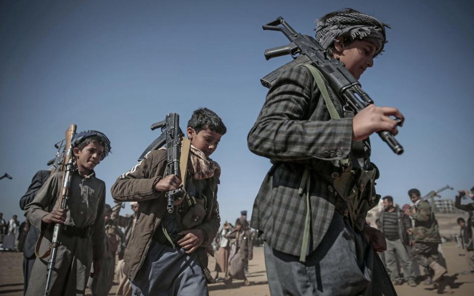 Boys shoulder weapons at a gathering of Houthi rebel fighters