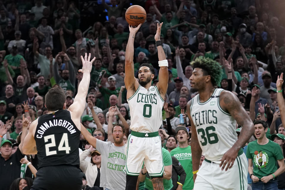 Boston Celtics forward Jayson Tatum (0) takes a shot at the basket as Milwaukee Bucks guard Pat Connaughton (24) defends while Celtics guard Marcus Smart (36) looks on during the second half of Game 7 of an NBA basketball Eastern Conference semifinals playoff series, Sunday, May 15, 2022, in Boston. The Celtics won 109-81. (AP Photo/Steven Senne)