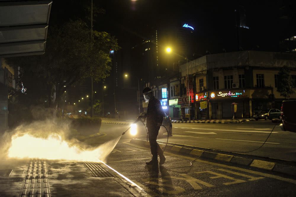 A Fire and Rescue personnel sprays disinfectant at a bus station to curb spread of Covid-19 in Kuala Lumpur March 31, 2020. — Picture by Shafwan Zaidon