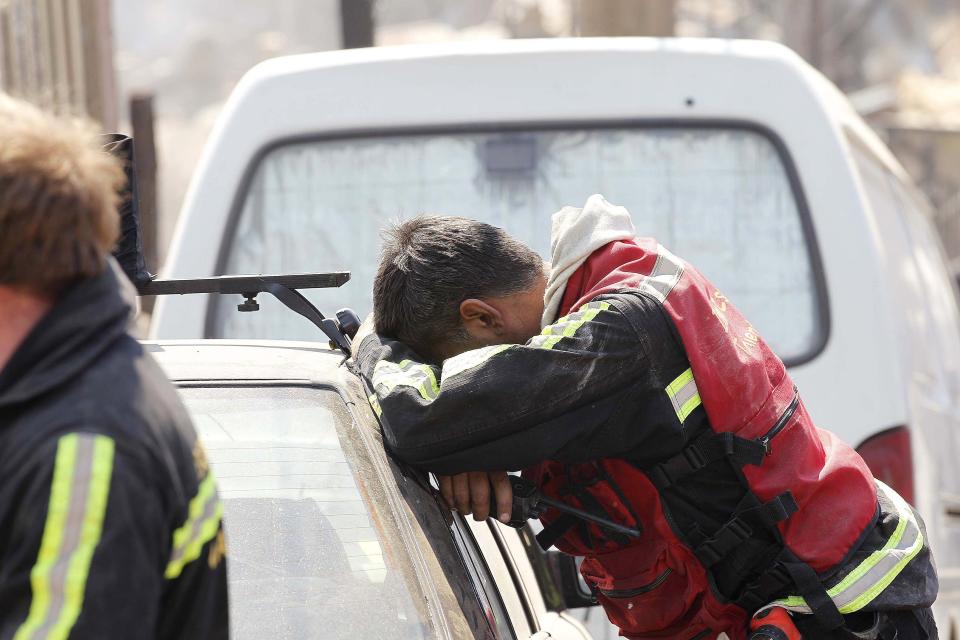 A rescue worker rests at the location where a forest fire burned several neighbourhoods in the hills in Valparaiso city, northwest of Santiago, April 13, 2014. At least 11 people were killed and 500 houses destroyed over the weekend by a fire that ripped through parts of Chilean port city Valparaiso, as authorities evacuated thousands and used aircraft to battle the blaze. REUTERS/Eliseo Fernandez (CHILE - Tags: SOCIETY ENVIRONMENT DISASTER)