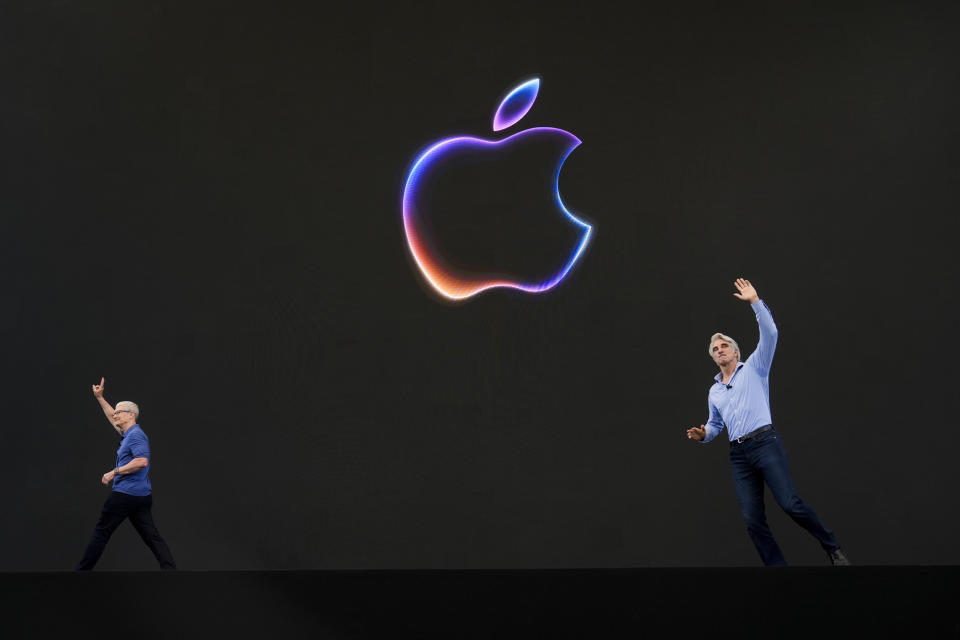 Apple CEO Tim Cook, left, exits the stage as Craig Federighi, senior vice president of software engineering, takes over during an announcement of new products at the Apple campus in Cupertino, Calif., on Monday, June 10, 2024. (AP Photo/Jeff Chiu)