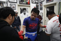 Soaked in sweat, boxer Manny Pacquiao gets his gloves removed after a workout at the Wild Card Boxing Club Monday, Jan. 14, 2019, in Los Angeles. The Filipino legend is in the winter of his career, gearing up for what could be one big last fight. Saturday's bout versus Broner isn't it, but Pacquiao trains with the knowledge that a second megafight against Floyd Mayweather could possibly be just months away if all goes well. (AP Photo/Jae C. Hong)