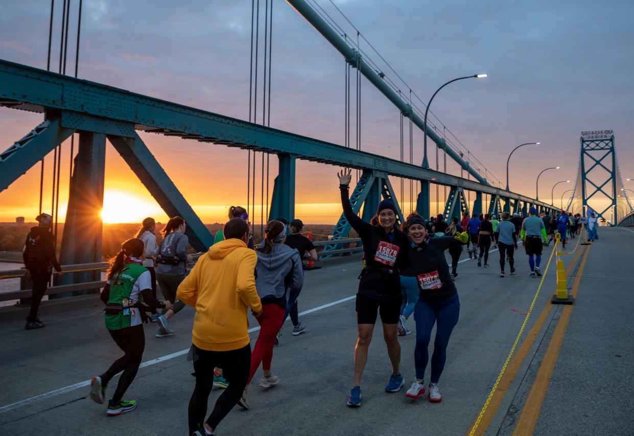 Shannon Anderson, left, and Amanda Kuchenberg pause for a photo as they make their way through the Ambassador Bridge at sunrise during the 45th Annual Detroit Free Press Marathon in Detroit on Oct. 16, 2022.