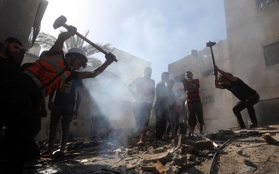Palestinians look for survivors under the rubble of a destroyed building following an Israeli airstrike in Khan Younis refugee camp, southern Gaza Strip