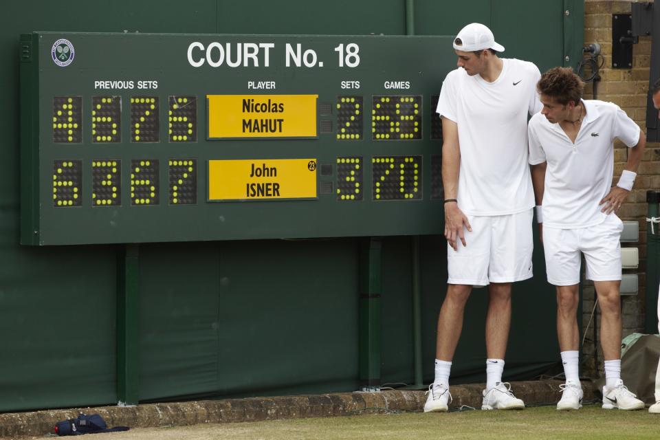 John Isner victorious near scoreboard with France Nicolas Mahut after winning Men's 1st Round at All England Club