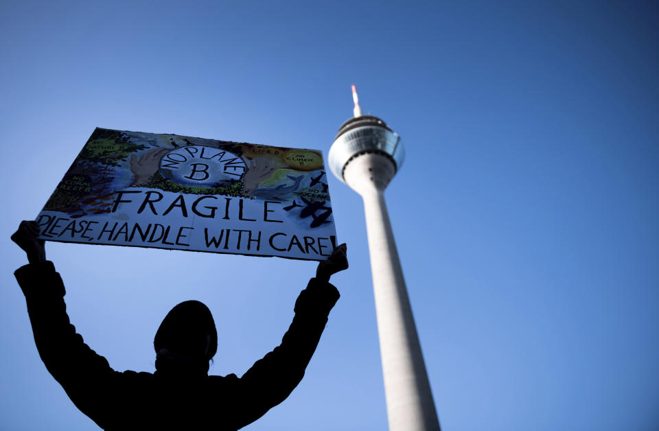 A demonstrator holds a sign in the air in front of the Rhine Tower, as he attends a Fridays for Future movement demonstration in Duesseldorf, Germany, Friday, Nov. 29, 2019. (Fabian Strauch/dpa via AP)