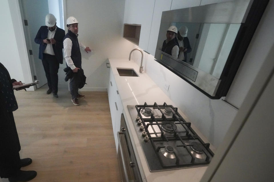 Joey Chilelli, right, managing director of real estate firm Vanbarton Group, and the company's senior project manager Malek Hajar, show the kitchen in a model apartment inside a high rise at 160 Water Street in Manhattan's financial district, undergoing conversion to residential apartments, Tuesday, April 11, 2023, in New York. (AP Photo/Bebeto Matthews)
