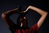 <p>An astronomy enthusiast looks through a pair of binoculars to see the lunar eclipse of a blood moon at Marina South Pier in Singapore July 28, 2018. REUTERS/Edgar Su </p>