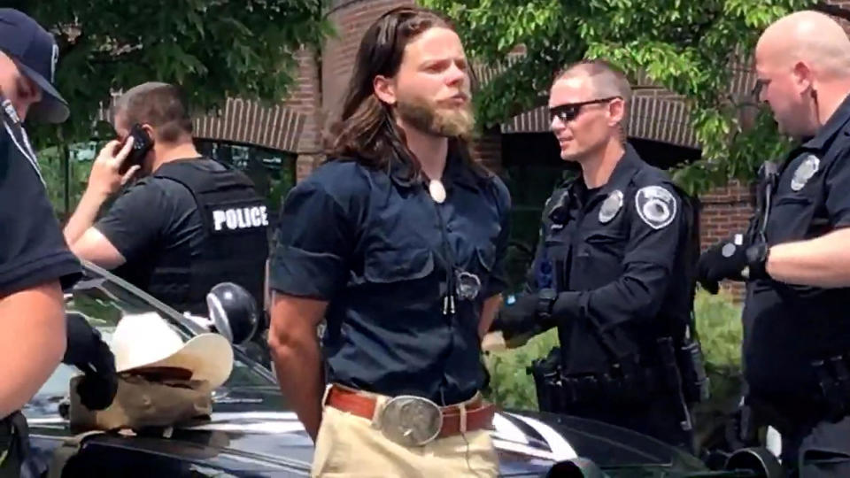 Thomas Rousseau, alleged founder and leader of white supremacist group Patriot Front, is held by police officers in Coeur d'Alene, Idaho, June 11, 2022, in this still image obtained from a social media video. / Credit: North Country Off Grid/YouTube/via Reuters