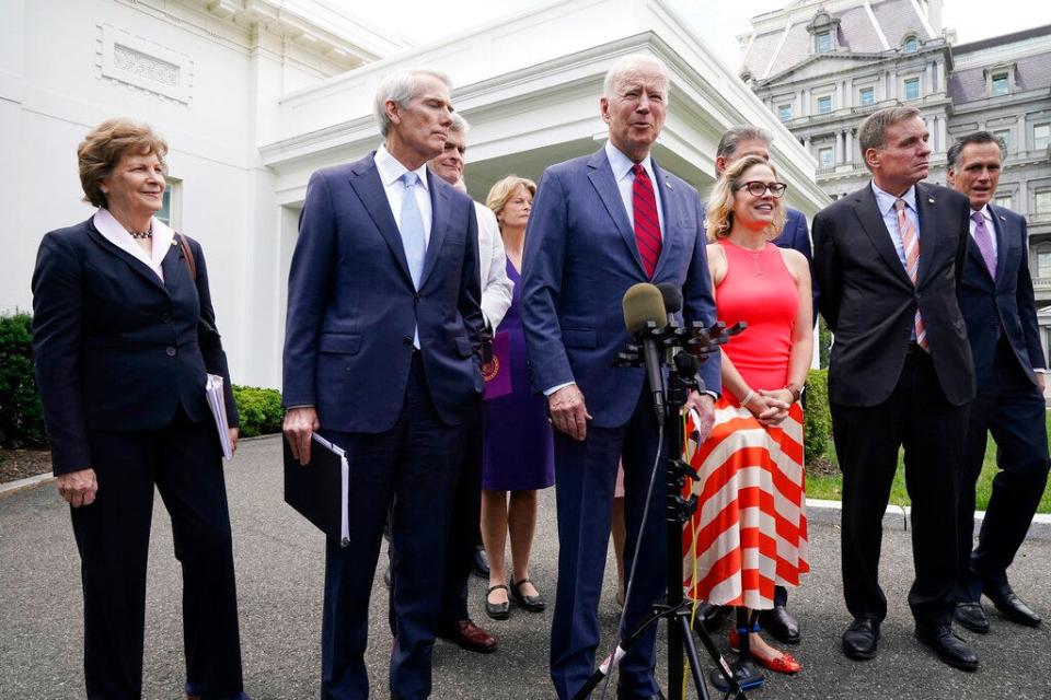 President Joe Biden, with a bipartisan group of senators, speaks Thursday June 24, 2021, outside the White House in Washington. Biden invited members of the group of 21 Republican and Democratic senators to discuss the infrastructure plan. From left are, Sen. Jeanne Shaheen, D-N.H., Sen. Rob Portman, R-Ohio, Sen. Bill Cassidy, R-La., Sen. Lisa Murkowski, R-Alaska, Biden, Sen, Joe Manchin, D-W.Va., Sen. Kyrsten Sinema, D-Ariz, Sen. Mark Warner, D-Va., and Sen. Mitt Romney, R-Utah.  (AP Photo/Jacquelyn Martin)