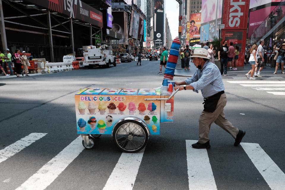 A vendor selling ices crosses the street in midtown Manhattan as temperatures reach into the 90s on July 21, 2022 in New York City. Much of the East Coast is experiencing higher than usual temperatures as a heat wave moves through the area forcing residents into parks, pools and beaches to escape the heat.