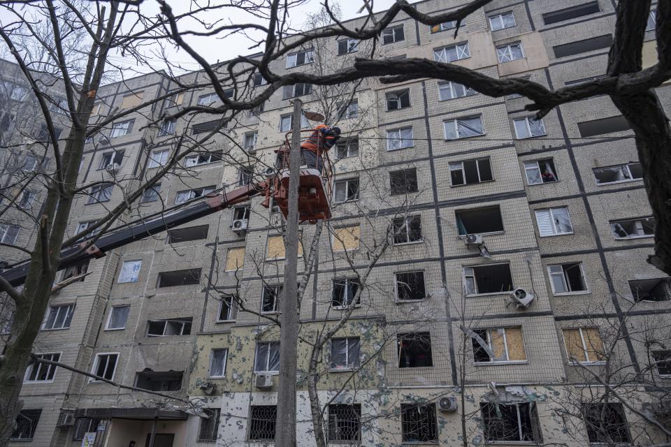 A municipal worker repairs electric cables near an apartment building that was destroyed by a Russian rocket attack in the southeastern city of Dnipro, Ukraine, Sunday, Jan. 15, 2023. (AP Photo/Evgeniy Maloletka)