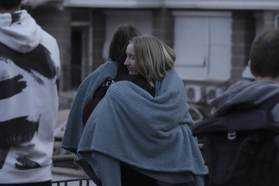 Residents warm themselves under the blanket as they evacuated from their multi-story apartment building which was damaged during Russian attack in Kyiv, Ukraine, Tuesday, May 30, 2023. (AP Photo/Roman Hrytsyna)