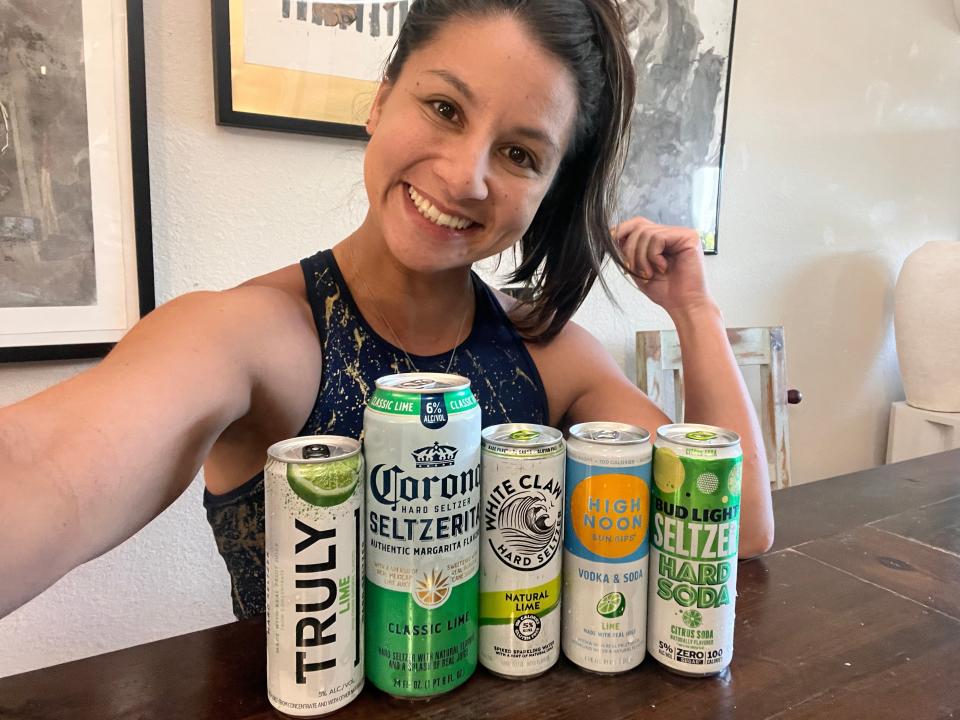 chelsea posing with 5 cans of lime hard seltzer on a kitchen table