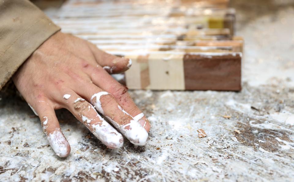 Reeve Carter glues wood together to secure pieces of what will become a cutting board or bowl.