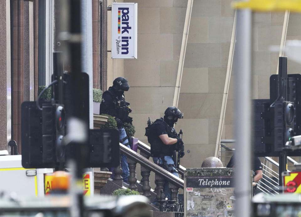 Armed police at the scene of an incident in Glasgow, Scotland, Friday June 26, 2020. Scottish police say the individual shot by armed police during an incident in Glasgow has died and that six other people including a police officer are in hospital being treated for their injuries.  (Andrew Milligan/PA via AP)