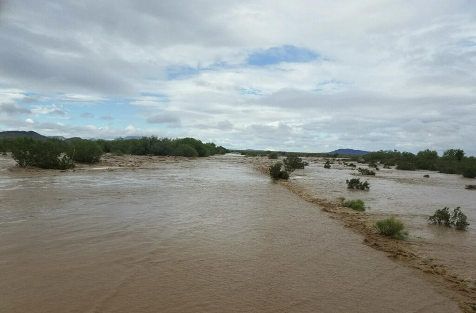 In this Tuesday, Oct. 2, 2018 photo provided by the Tohono O'odham Nation Dept. of Public Safety, is flooding near the Kohatk Village in Pinal County, Ariz. Menagers Dam that had been at risk of breaking and flooding the small village held steady Wednesday, Oct. 3, as the lake behind it receded after being swollen with runoff from the remnants of Tropical Storm Rosa. (Tohono O'odham Nation Dept. of Public Safety via AP)