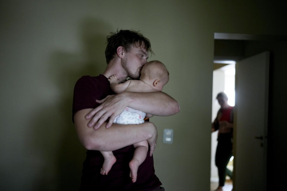 Andrei Ushakov acaricia a su hijo nacido en Argentina, Lev Andrés, en su casa de Mendoza, Argentina, el martes 14 de febrero de 2023. (AP Foto/Natacha Pisarenko)