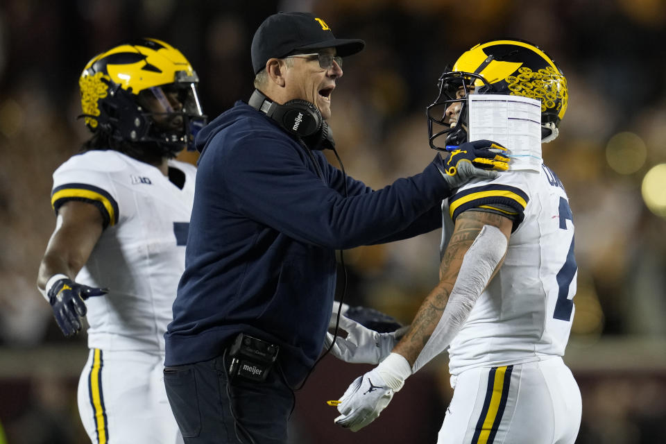 Michigan head coach Jim Harbaugh, center, celebrates with running back Blake Corum, right, after Corum scored a touchdown during the first half of an NCAA college football game against Minnesota, Saturday, Oct. 7, 2023, in Minneapolis. (AP Photo/Abbie Parr)