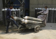 Workers load oxygen cylinders onto a hand cart to be carried inside the COVID-19 wards at a government run hospital in Jammu, India, Friday, May 7, 2021. With coronavirus cases surging to record levels, Indian Prime Minister Narendra Modi is facing growing pressure to impose a harsh nationwide lockdown amid a debate whether restrictions imposed by individual states are enough. (AP Photo/Channi Anand)
