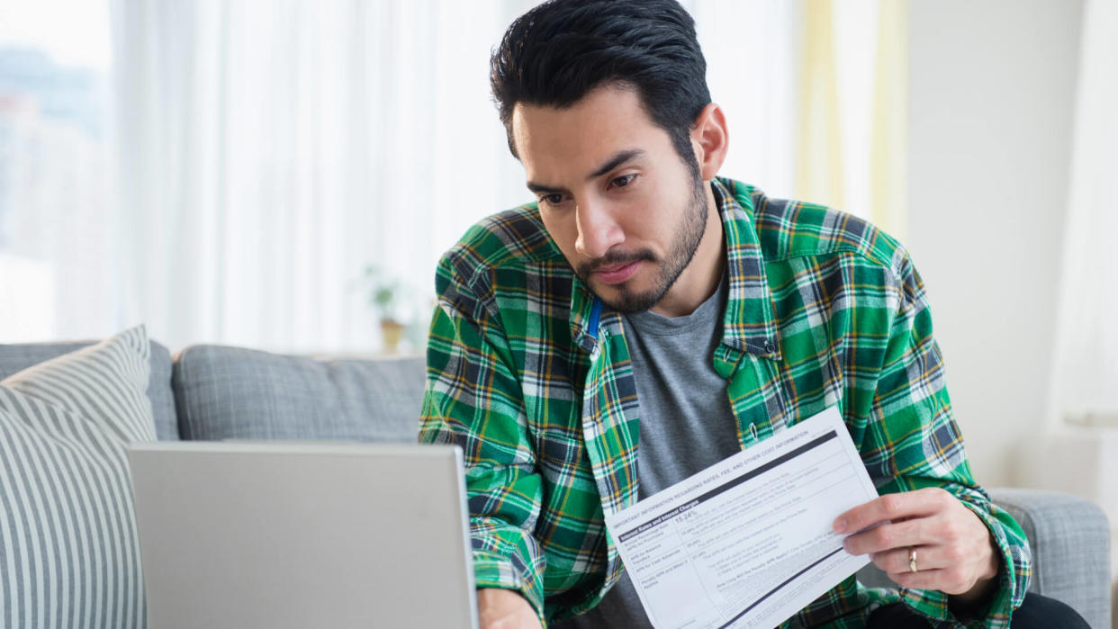 Mixed race man paying bills in living room.