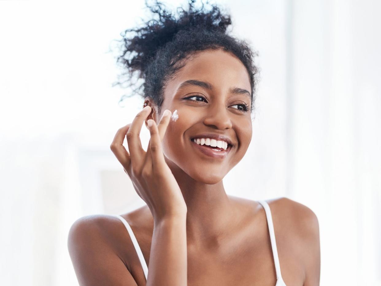 Shot of a beautiful young woman applying moisturiser to her face