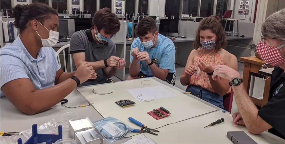 More than 230 Robertsville Middle School students had hands-on experience with flight hardware while building and testing the RamSat spacecraft. Here, Peter Thornton (right) is working with four students on the project during the pandemic.